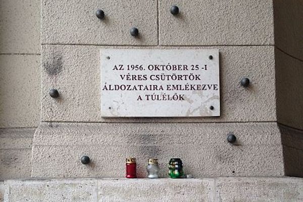 The memorial placard reads: “Dedicated to the victims of Bloody Thursday, October 25th, 1956. —The Survivors.”